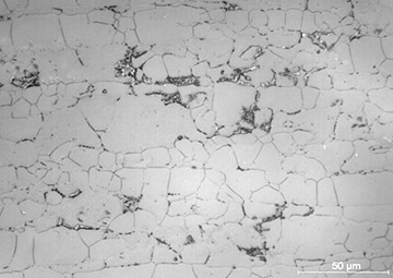 Fig. 9 — Micrografia com ataque eletrolítico de um aço inoxidável duplex apresentando as fases austenita (mais lisa), ferrita e sigma (pontos escuros). Réplica trazida de campo e analisada no laboratório.